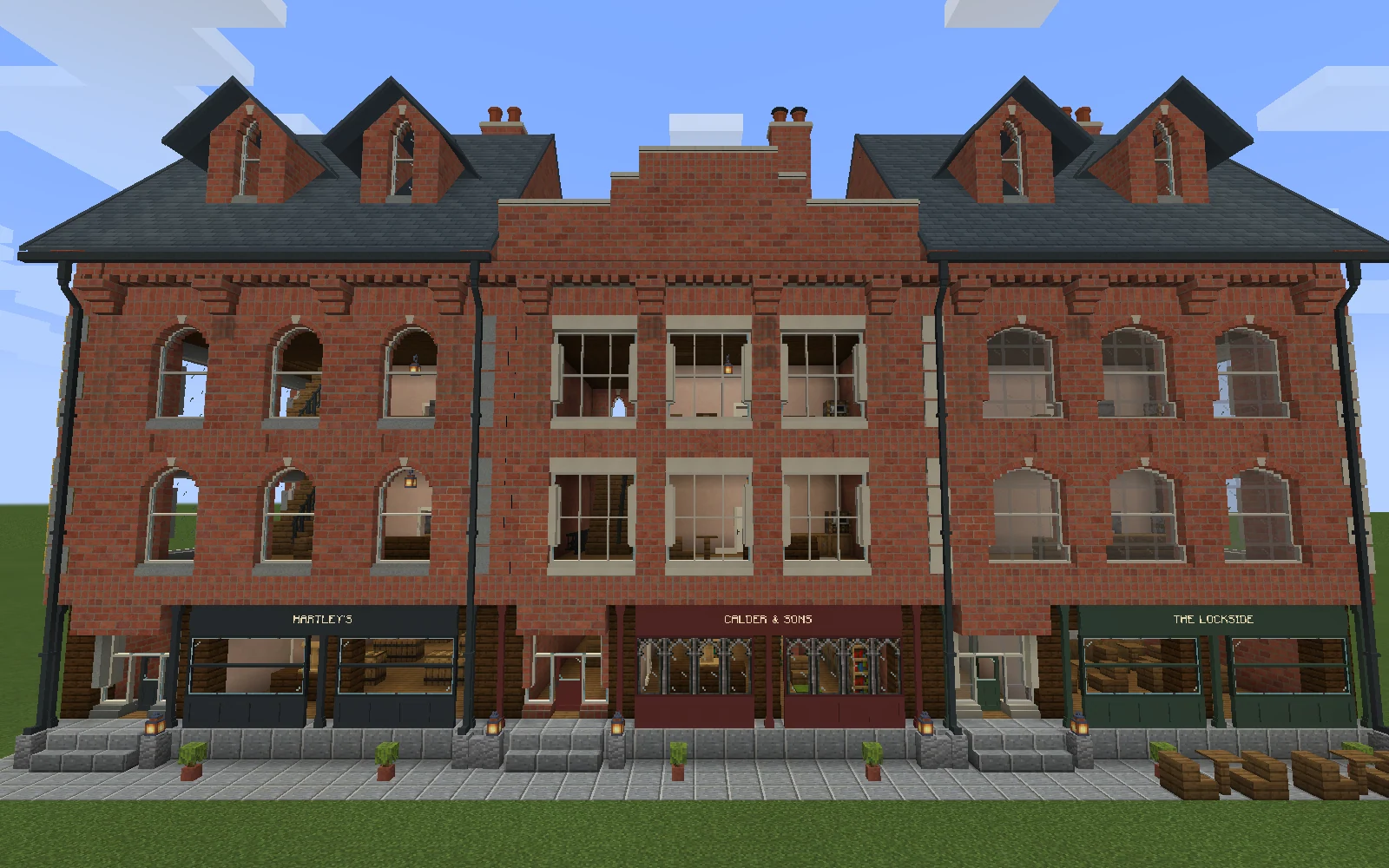 Three brick shopfronts with distinct charcoal, oxblood and green fascias, beneath finished slate dormers and a stepped central parapet.