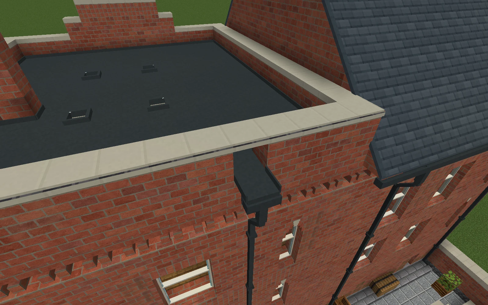 A short metal scupper passes through the brick parapet beneath limestone coping, leading over a gutter and offset downpipe.