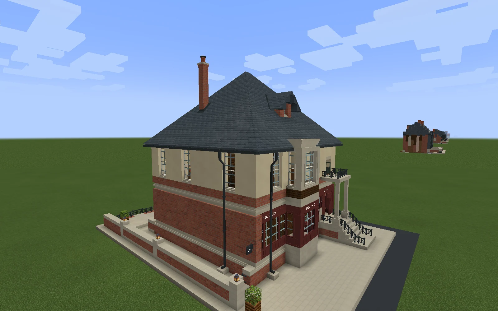 The completed corner pub has a slate roof, chimney, dormer, cream upper storey, oxblood shopfront and small charcoal sign beside its enclosed passage.