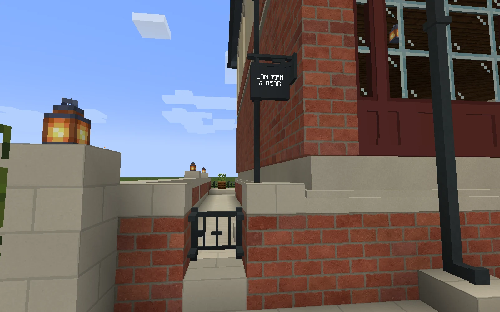A charcoal projecting Lantern & Gear sign is mounted above the iron gate into the pub side passage.